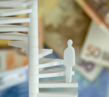 Figura en las escaleras con billetes de banco al fondo (imagen simbólica) © Westend61 / Achim Sass