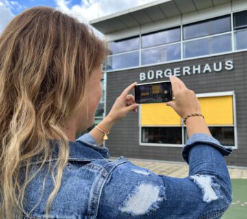 Frau beim Fotografieren des Bürgerhauses © Stadt Burghausen