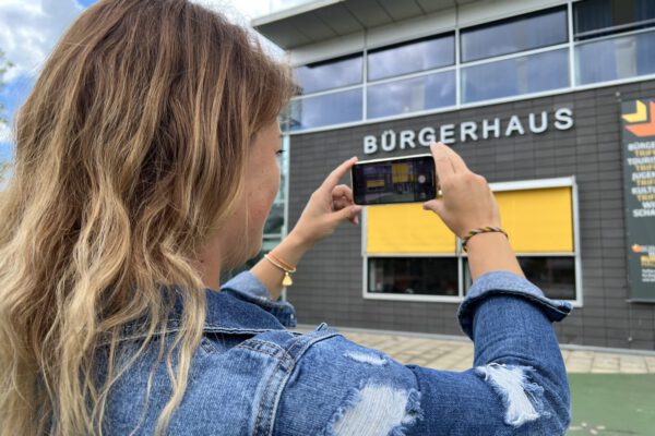 Frau beim Fotografieren des Bürgerhauses © Stadt Burghausen