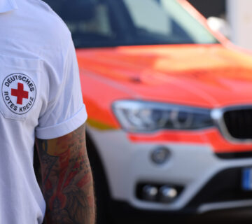 Sanitäter des Deutschen Roten Kreuzes mit Notarztwagen im Hintergrund © Gerhard Nixdorf
