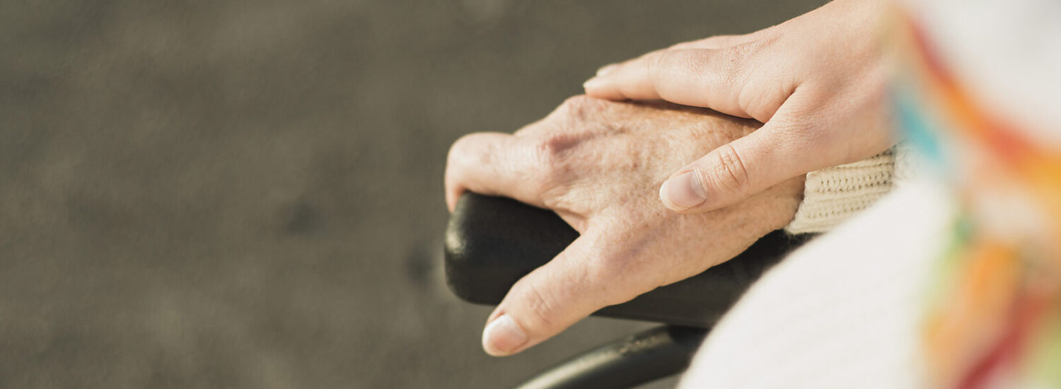 Hand hält Hand einer älteren Person im Rollstuhl © Westend61 / Uwe Umstätter