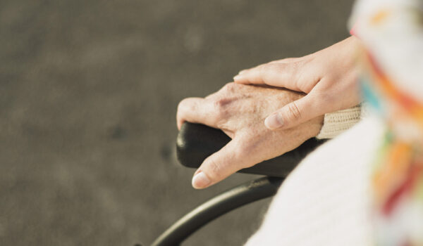 Hand hält Hand einer älteren Person im Rollstuhl © Westend61 / Uwe Umstätter