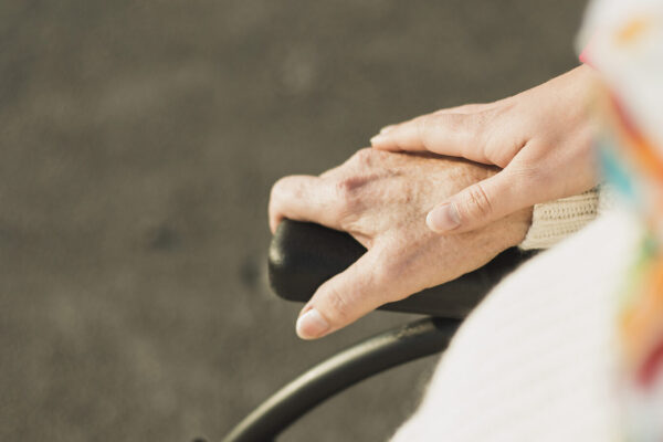 Hand hält Hand einer älteren Person im Rollstuhl © Westend61 / Uwe Umstätter