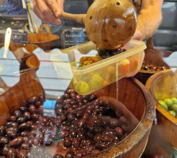 Burghauser Wochenmarkt: Verkäufer füllt Oliven in ein mitgebrachtes Gefäß einer Kundin © Stadt Burghausen/ebh