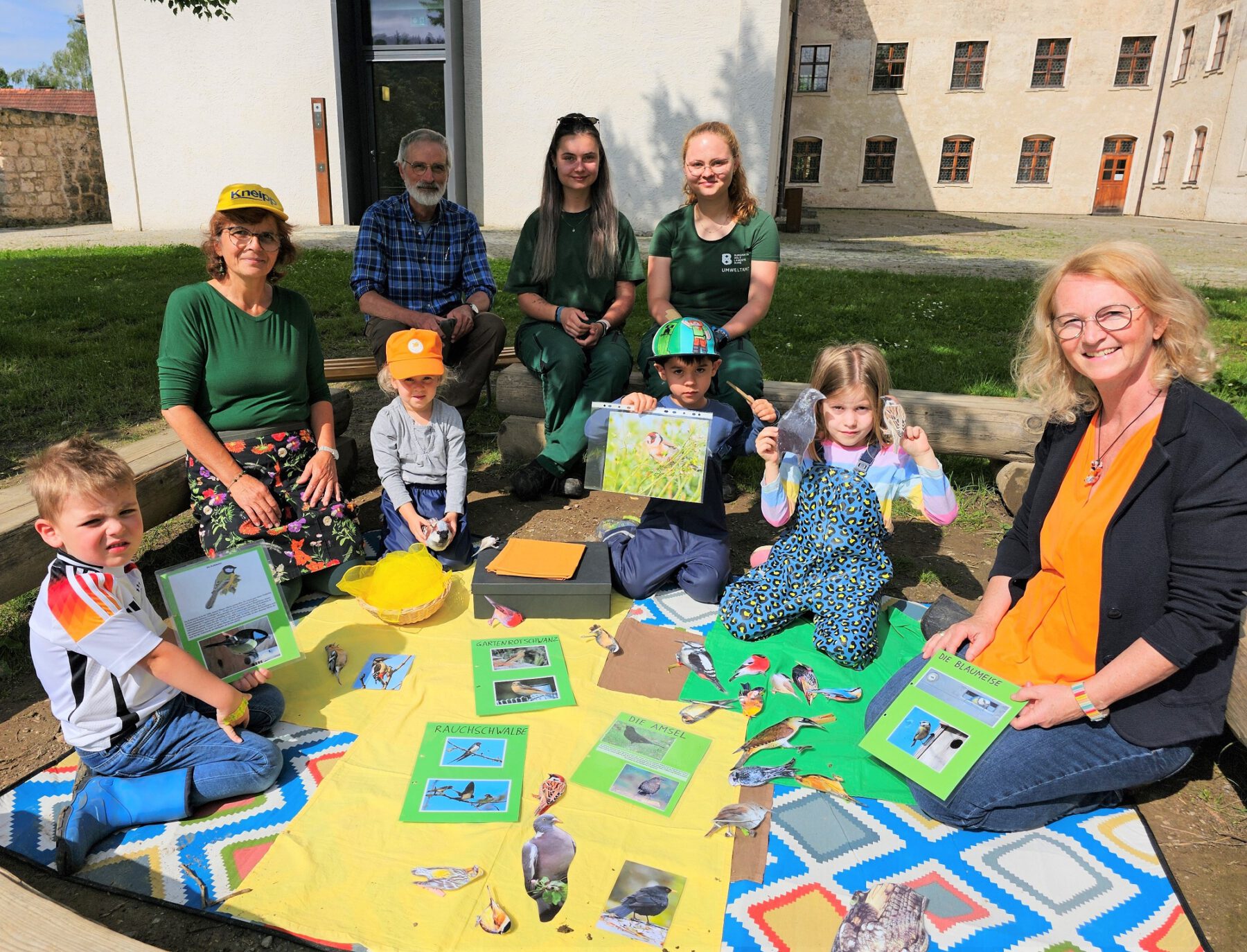 Die Kinder lernten einiges über die Vögel in ihrem Garten mithilfe der Vogelbox und bunten Zeichnungen. Andrea Ripszam (2.v.l.), Leiterin der Klosterspatzen, Holger Lundt (hinten links), die beiden FÖJlerinnen Ariane Wacker (hinten Mitte) und Judith Schärl (hinten rechts) sowie Marion Bernecker (r.) von den Klosterspatzen © Stadt Burghausen/ebh