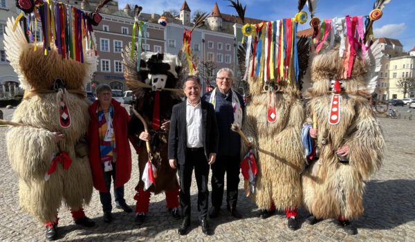 Foto: Im Kreise wilder Kerle: Elisabeth Hübner (2 v.l.), Referentin des Burghauser Partnerstadtvereins für Ptuj, Erster Bürgermeister Florian Schneider und Zweiter Bürgermeister Norbert Stranzinger (Mitte), umringt von einigen Ptujer Kurenten mit ihren farbenprächtigen Masken und mächtigen Knüppeln. Fotocredit: Stadt Burghausen/sast