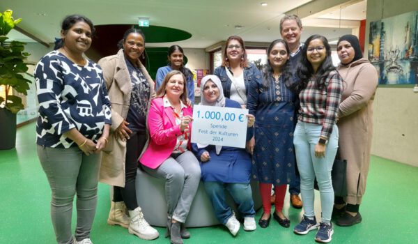 Foto: Acht engagierte Bürgerinnen und Bürger übergeben eine Spende von 1.000 Euro an Sozialamtsleiterin Elisabeth Rummert (sitzend links) und Ersten Bürgermeister Florian Schneider: Swathi Kotha, Mery Teshome, Yashaswi Kotha, Haifa Ragab, Rabiaa Mohammed, Kinjal Bhayani, Jahanvi Modi und Sabah Turkmane. Fotocredit: Stadt Burghausen / Haus der Familie