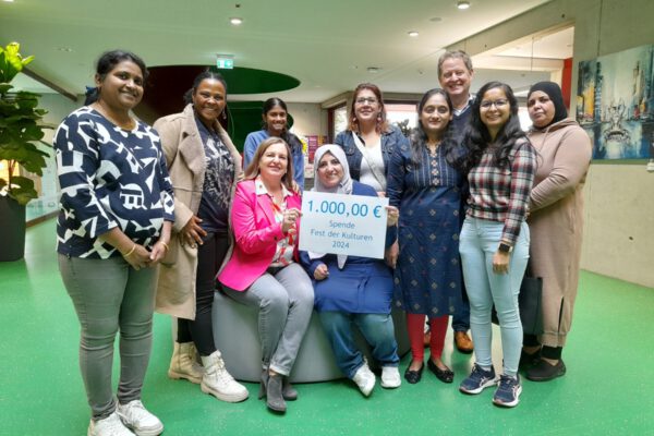 Foto: Acht engagierte Bürgerinnen und Bürger übergeben eine Spende von 1.000 Euro an Sozialamtsleiterin Elisabeth Rummert (sitzend links) und Ersten Bürgermeister Florian Schneider: Swathi Kotha, Mery Teshome, Yashaswi Kotha, Haifa Ragab, Rabiaa Mohammed, Kinjal Bhayani, Jahanvi Modi und Sabah Turkmane. Fotocredit: Stadt Burghausen / Haus der Familie