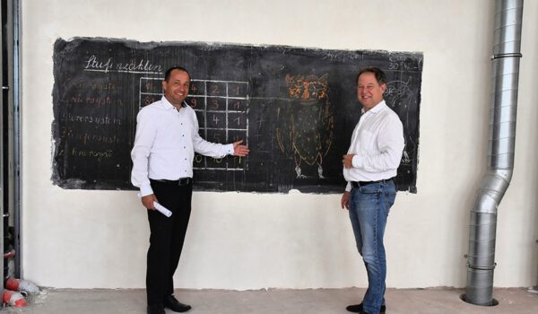 Zeugen der Vergangenheit: Stadtbaumeister Manfred Winkler (l.) und Erster Bürgermeister Florian Schneider begutachten eine Schultafel mit Beschriftung wohl aus den 1960er Jahren, die vor dem Umbau hinter einer Schrankwand versteckt war. Sie wird nun wieder sichtbar in das neue Klassenzimmer integriert. Fotocredit: Stadt Burghausen/tg