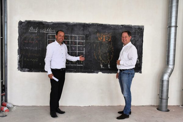 Zeugen der Vergangenheit: Stadtbaumeister Manfred Winkler (l.) und Erster Bürgermeister Florian Schneider begutachten eine Schultafel mit Beschriftung wohl aus den 1960er Jahren, die vor dem Umbau hinter einer Schrankwand versteckt war. Sie wird nun wieder sichtbar in das neue Klassenzimmer integriert. Fotocredit: Stadt Burghausen/tg Zeugen der Vergangenheit: Stadtbaumeister Manfred Winkler (l.) und Erster Bürgermeister Florian Schneider begutachten eine Schultafel mit Beschriftung wohl aus den 1960er Jahren, die vor dem Umbau hinter einer Schrankwand versteckt war. Sie wird nun wieder sichtbar in das neue Klassenzimmer integriert. Fotocredit: Stadt Burghausen/tg