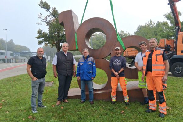 Für vier Wochen wird die 1000 nun an der Hauptpforte von WACKER stehen – dorthin begleiteten sie (v.l.) Bauhofleiter Peter Schweikl, Zweiter Bürgermeister Norbert Stranzinger, Michael Strasser (WACKER) sowie das Transportteam vom städtischen Bauhof. Fotocredit: Stadt Burghausen/tg