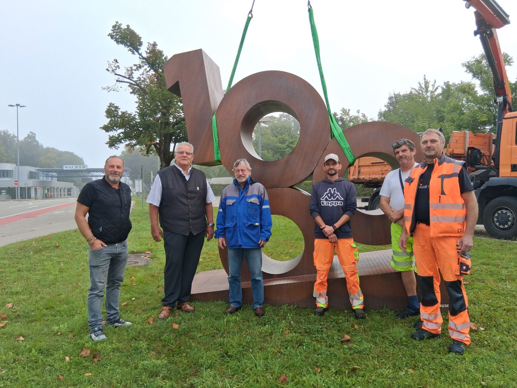 Für vier Wochen wird die 1000 nun an der Hauptpforte von WACKER stehen – dorthin begleiteten sie (v.l.) Bauhofleiter Peter Schweikl, Zweiter Bürgermeister Norbert Stranzinger, Michael Strasser (WACKER) sowie das Transportteam vom städtischen Bauhof. Fotocredit: Stadt Burghausen/tg