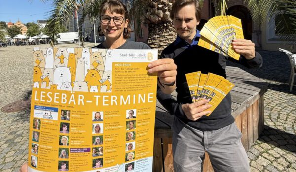 Die Leiterin der Stadtbibliothek Christin Moll und Mitarbeiter Patrick Brenner zeigen das neue Programm „Lesebär aktuell“ 2025 / 2026. Fotocredit: Stadt Burghausen