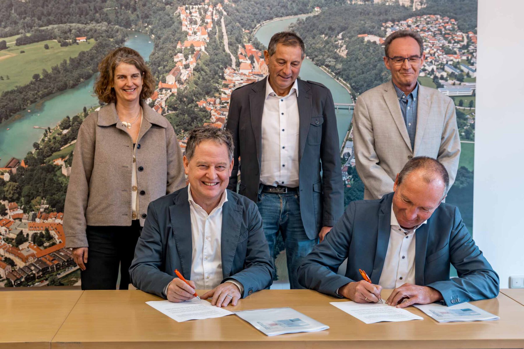 Erster Bürgermeister Florian Schneider und Amtskollege von Kirchweihdach Robert Moser unterzeichnen die Verträge zur Lieferung der Naturwärme nach Burghausen. Dahinter stehend Tanja Erb als Geschäftsführerin der EBG, Josef Steiner als Geschäftsführer der Naturwärme GmbH und Michael Bock als Leiter der Stadtwerke Burghausen. Fotocredit: Manuela Fuchs