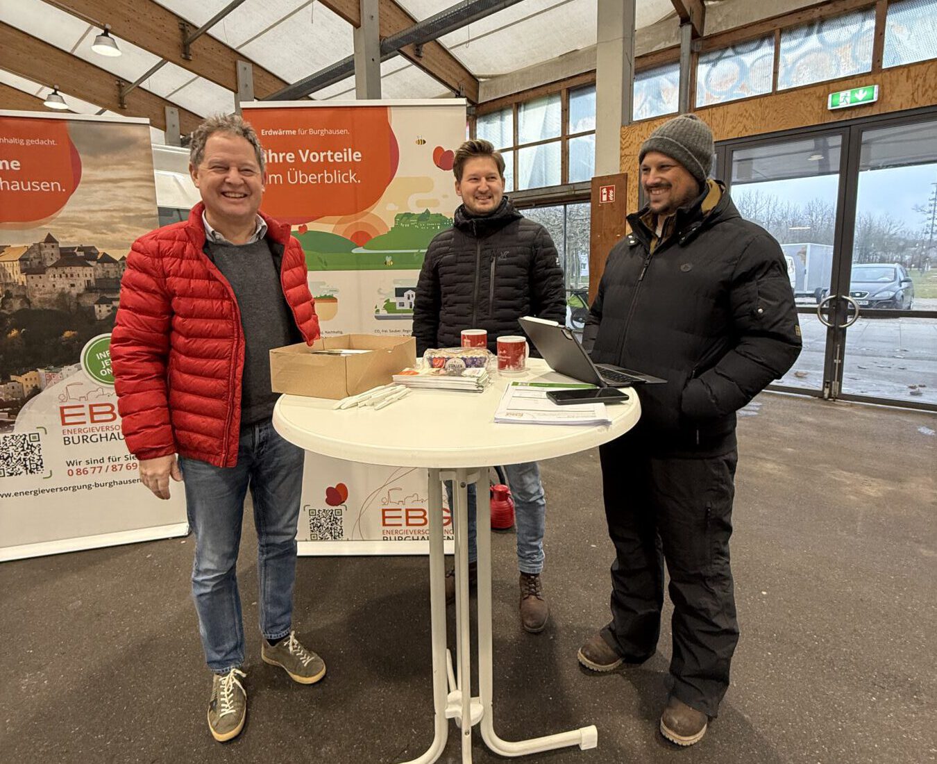 Erster Bürgermeister Florian Schneider schaut beim Beratungsteam am Wochenmarkt in der Messehalle vor-bei. Umweltingenieur Stephan Göbl und Martin Kohl von der EBG werden vor allem nach den Kosten für den Hausanschluss und Terminen der Ausbaustufen gefragt. Fotocredit: Stadt Burghausen / Königseder