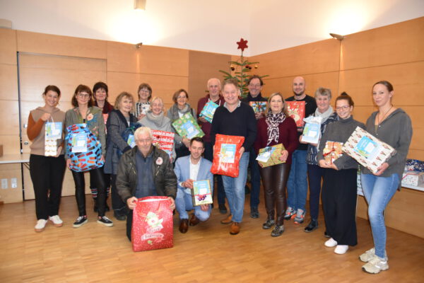 Erster Bürgermeister Florian Schneider übergibt die liebevoll verpackten Geschenke an die elf Einrichtungen, die die Wünsche ans Bürgerhaus-Team übermittelt haben. Fotocredit: Stadt Burghausen / köx