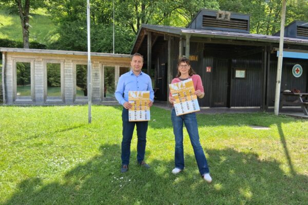 2026_05_13_Stadt_Burghausen_Lesebär_unterwegs Sie freuen sich auf den Lesebär: Bäderleiter Stefan Sajdak und Büchereileiterin Christin Moll an einem der beiden Vorleseorte am Wöhrsee – im Freibad finden ebenfalls zwei Vorlesetermine statt. Fotocredit: Stadt Burghausen/tg