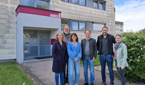 2026_05_18_Stadt_Burghausen_EBG_Fernwärme_Gluckstraße_Ankerkunde : Die Bewohner der Gluckstraße 2-9 können künftig mit sicherer und nachhaltiger Energie durch Fernwärme heizen. Zum Vor-Ort-Termin kamen (v.l.) Tanja Erb, Geschäftsführerin EBG, Umweltreferent und Beirat Gunter Strebel, Mit-Eigentümerin und Beirätin Christin Moll, Erster Bürgermeister Florian Schneider, Stefan Huber (EBG) und Hausverwalterin Katrin Bader-Schwaninger.