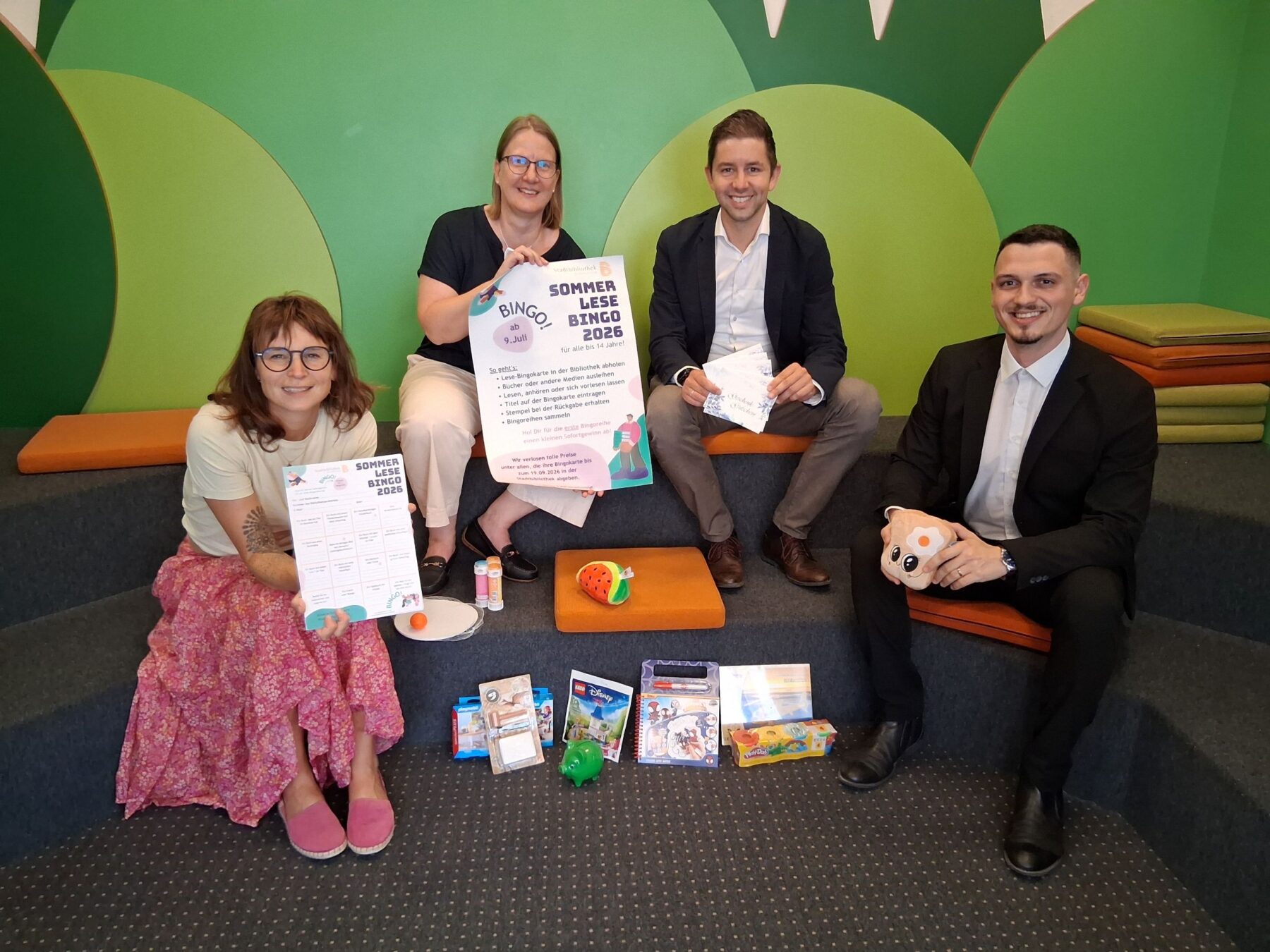 Foto: Vier Stempel einsammeln und – Bingo! So funktioniert der Sommerlesespaß in der Stadtbibliothek Das Team der Stadtbibliothek mit Leiterin Christin Moll und Mitarbeiterin Monika Vornehm ist bereit für den Kinderansturm, Sebastian Rauschecker und David Gergely Komaromi von der Sparkasse Burghausen sponserten dieses Mal die Sofortgewinne Fotocredit: Stadt Burghausen/tg