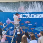 Farbenrausch in der Unterwasserwelt: Graffiti Künstler Martin Keindl leitete die Kinder bei der Umsetzung ihrer kreativen Ideen an, die Kinder reichten ihm die Spraydosen für den Schriftzug  Fotocredit: Stadt Burghausen/tg