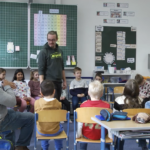 Szene aus dem neuen Film „Starke Jugend“, zu sehen auf dem YouTube Kanal der Stadt Burghausen: Martin Höllmüller (stehend) und Germain Bennett (l ) spielen mit den Schülerinnen und Schülern echte Situationen aus ihrem (Schul )Alltag durch  Fotocredit: Stadt Burghausen