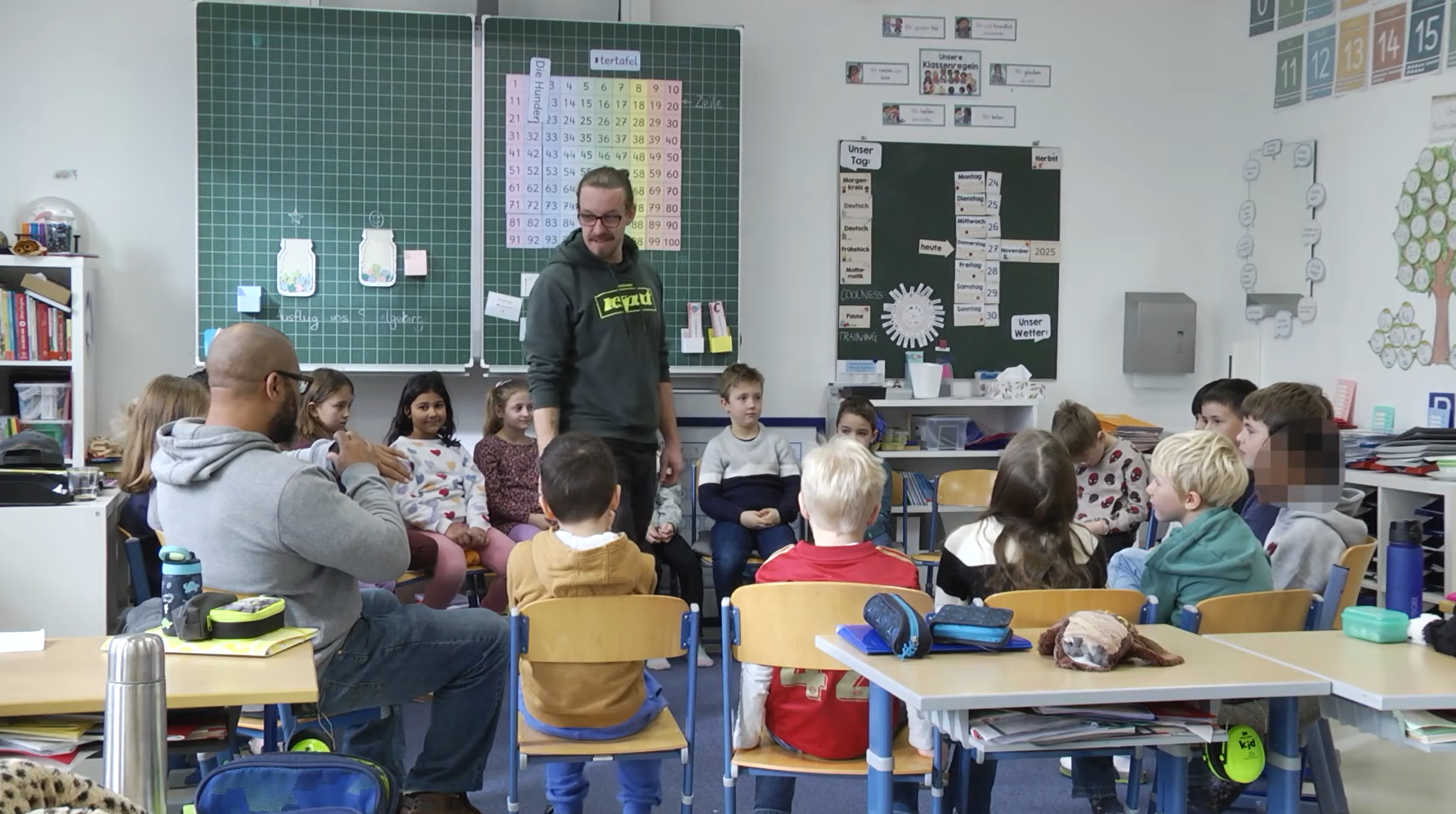 Szene aus dem neuen Film „Starke Jugend“, zu sehen auf dem YouTube Kanal der Stadt Burghausen: Martin Höllmüller (stehend) und Germain Bennett (l ) spielen mit den Schülerinnen und Schülern echte Situationen aus ihrem (Schul )Alltag durch Fotocredit: Stadt Burghausen