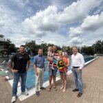 Erster Bürgermeister Florian Schneider begrüßte gemeinsam mit Bäderleiter Stefan Sajdak und Florian Moser die Familie Kornberger aus Ampfing als 100 000  Badegäste der Freibadsaison 2026 im Burghauser Freibad  Zur Überraschung gab es Blumen für Susanne Kornberger, Taucherbrillen für Teresa und Valentina sowie eine Saisonkarte 2027 für die ganze Familie  Fotocredit: Stadt Burghausen / köx