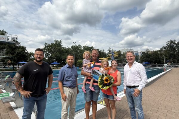 PM 156 Freibad Fam Kronberger 100.000 Badegast Erster Bürgermeister Florian Schneider begrüßte gemeinsam mit Bäderleiter Stefan Sajdak und Florian Moser die Familie Kornberger aus Ampfing als 100.000. Badegäste der Freibadsaison 2026 im Burghauser Freibad. Zur Überraschung gab es Blumen für Susanne Kornberger, Taucherbrillen für Teresa und Valentina sowie eine Saisonkarte 2027 für die ganze Familie. Fotocredit: Stadt Burghausen / köx