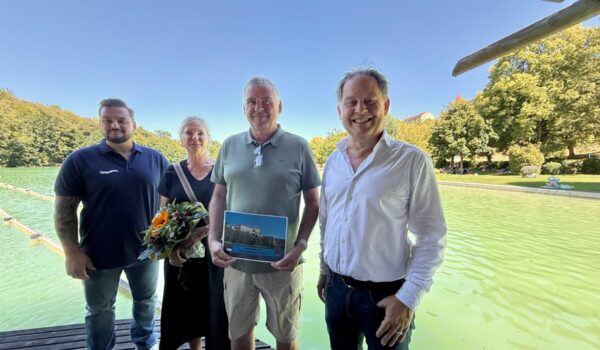 Erster Bürgermeister Florian Schneider und Bäderleiter Florian Moser begrüßten das Ehepaar Rosmarie und Richard Siegerd aus Haiming als 100.000 Badegäste. Das Ehepaar ist Stammgast und besucht den See mindestens vier Mal pro Woche. „Wir schätzen die sehr gute Wasserqualität und die natürliche Beschattung. Das Flair ist einzigartig und wenn wir am Vormittag da sind ist es auch noch schön ruhig“, so die Siegerds. Als kleine Aufmerksamkeit überreicht das Stadtoberhaupt Blumen und eine Saisonkarte für das nächste Jahr.