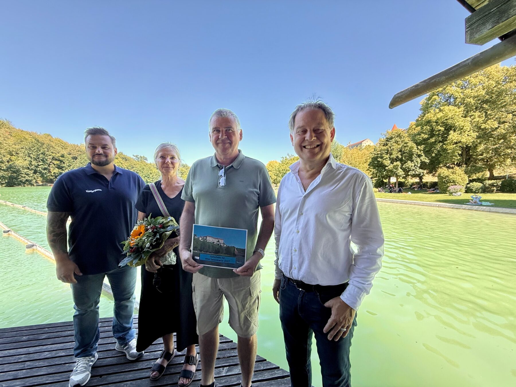 Erster Bürgermeister Florian Schneider und Bäderleiter Florian Moser begrüßten das Ehepaar Rosmarie und Richard Siegerd aus Haiming als 100 000 Badegäste Das Ehepaar ist Stammgast und besucht den See mindestens vier Mal pro Woche „Wir schätzen die sehr gute Wasserqualität und die natürliche Beschattung Das Flair ist einzigartig und wenn wir am Vormittag da sind ist es auch noch schön ruhig“, so die Siegerds Als kleine Aufmerksamkeit überreicht das Stadtoberhaupt Blumen und eine Saisonkarte für das nächste Jahr